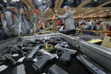  - 
              FILE - In this Saturday, Jan. 26, 2013 file photo, handguns appear on display at the table of David Petronis of Mechanicville, N.Y., standing with rifle, who owns a gun store, during th