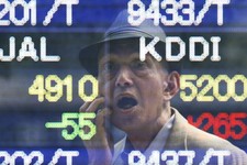  - 
              A man is reflected on the electronic board of a securities firm in Tokyo Thursday, May 16, 2013. The benchmark Nikkei 225 stock index rose to 15,139.56 early Thursday before falling bac