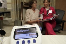  - 
              This photo taken Jan. 30, 2013 shows a Health Buddy electronic monitoring device sitting on the bed as patient Marlena Bechtel-Rysdam, left, from Elgin, Ore., goes over training materia