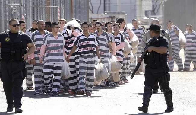 FILE - In this Feb. 4, 2009, file photo, approximately 200 convicted illegal immigrants are handcuffed together and moved into a separate area of Tent City, by order of Maricopa County