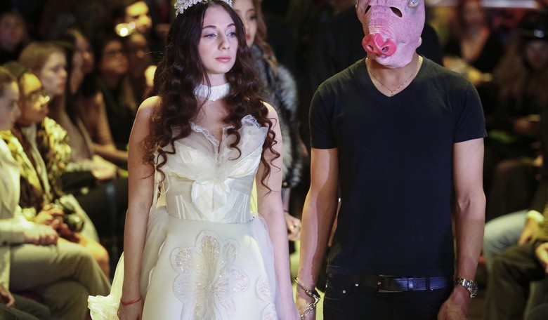 #MeToo Fashion Show Features Pig-Faced Men Handcuffed to Models with Angel Wings