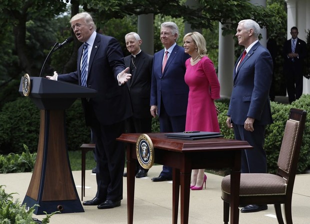 FILE - In this Thursday, May 4, 2017 file photo, President Donald Trump speaks in the Rose Garden of the White House in Washington, before signing an executive order aimed at easing an IRS rule limiting political activity for churches. From second from left are, Cardinal Donald Wuerl is the Archbishop of Washington, Pastor Jack Graham, Paula White, senior pastor of New Destiny Christian Center in Apopka, Fla. and Vice President Mike Pence. (AP Photo/Evan Vucci)