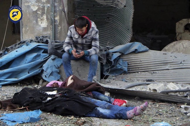 This photo provided by the Syrian Civil Defense White Helmets, which has been authenticated based on its contents and other AP reporting, shows a Syrian boy sittiing next to bodies after artillery fire struck the Jub al-Quba district in Aleppo, Syria, Wednesday, Nov. 30, 2016. Syrian activists say at least 21 people have been killed in an artillery barrage on a housing area for those displaced in rebel-held eastern Aleppo. (Syrian Civil Defense White Helmets via AP)