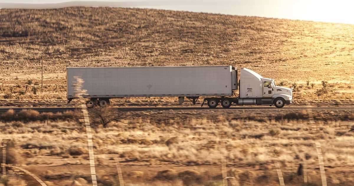 White semi truck driving down a rural road. (Credit: Daphne Fecheyr)