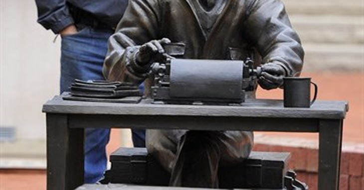 In this photo taken on Thursday, Oct. 9, 2014, sculptor Tuck Langland stands behind his work during the installation of a bronze Ernie Pyle statute outside Franklin Hall at Indiana Univ