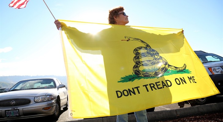 Leslie Corp holds up an American flag and the Gadsden flag while waiting outside of Roseburg Municipal Airport for President Barack Obama's arrival in Roseburg, Ore., Friday, Oct. 9, 20