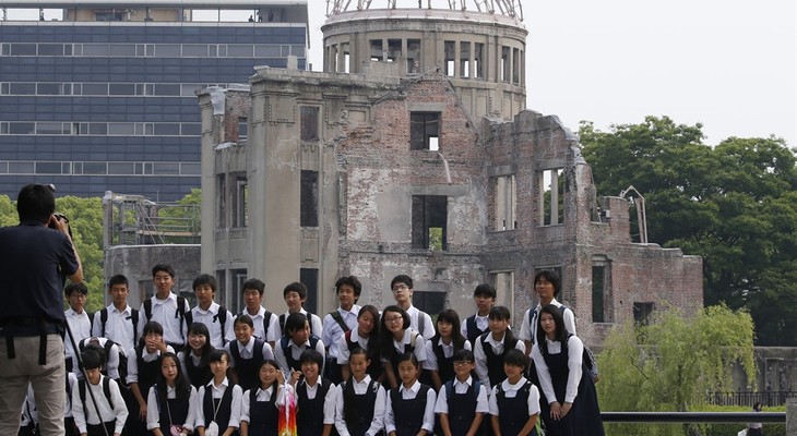 School children pose for a group photo with the Atomic Bomb Dome as a backdrop in Hiroshima Peace Memorial Park in Hiroshima, western Japan, Friday, May 27, 2016. Convinced that the tim