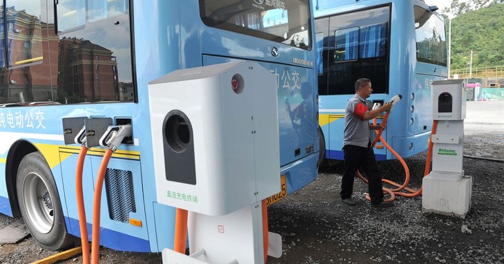 In this July 15, 2016, photo, a driver charges an electric bus made by King Long United Automotive Industry at a terminal in Lin'an city in eastern China's Zhejiang Province. China's el