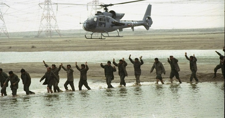 FILE - In this Monday, February 25, 1991 file photo, a Kuwaiti military helicopter herds Iraqi prisoners, arms in the air, across a stream in southeastern Kuwait, as Operation Desert St